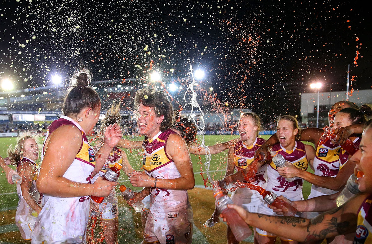 The Brisbane Lions sing their team song and spray Gatorade at Isabella Ayre and Nat Exon, after winning their AFLW match against the Carlton Blues at Melbourne’s Ikon Park.